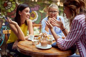 A group of female students is enjoying a friendly talk while having a drink in a bar garden....