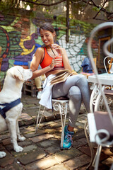 A young girl enjoying a drink and company of her dog at a bar. Leisure, bar, outdoor, friendship