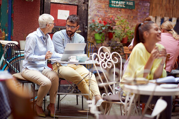 An elderly woman and her young male friend have an interesting talk while spending free time at bar's garden together. Leisure, bar, friendship, outdoor