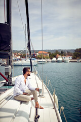 A young man is enjoying a view while sitting on a yacht at sea and using a tablet. Summer, sea, vacation