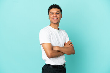 Young African American man isolated on blue background with arms crossed and happy