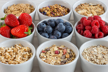 granola, cereals and berries in small bowls, various delicious ingredients for breakfast