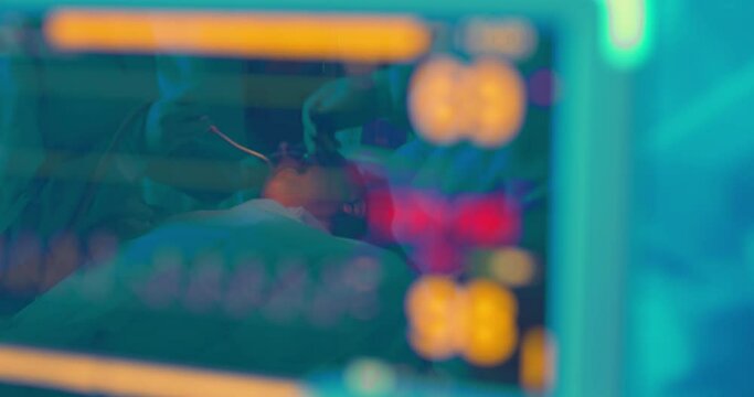 Close-up patient's monitor screen with diagrams and male patient is under anesthesia having dental treatment by the dentist is reflected on the screen with diagram of oxygen saturation and pressure.