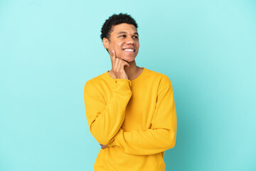 Young African American man isolated on blue background thinking an idea while looking up