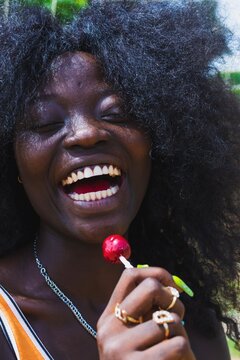 Girl laughing with lollipop close to mouth.