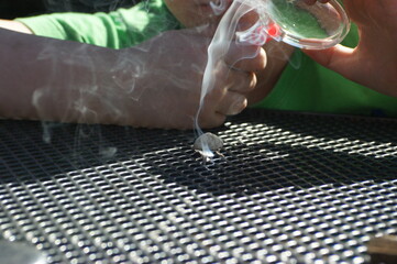 Unrecognizable boy Starting a Fire with a Magnifying Glass outdoors with selective focus