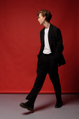 Stylish young guy with lush blond hair and beautiful skin in a black jacket, pants and white...