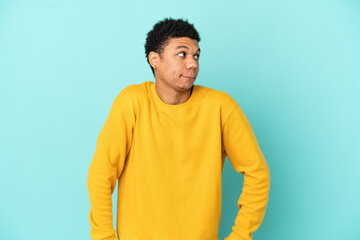 Young African American man isolated on blue background having doubts while looking up