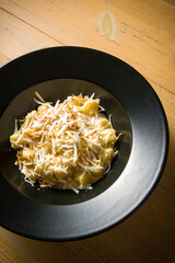 plate of gnocchi with grated cheese, over wooden table. Detail