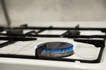 Close-up of a gas burner from a kitchen stove. Gas stove with a burning blue gas flame.