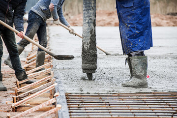 concrete pouring from a hose by workers at a shallow depth of field