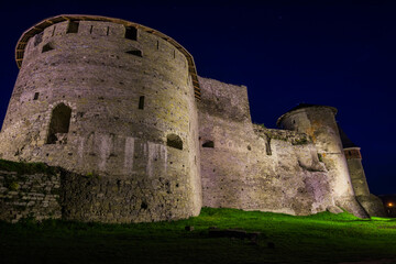 Fototapeta na wymiar View of the towers and walls of the Kamianets-Podilskyi Castle in the night. Stone bastion of an ancient castle. Beautiful stone castle on the hill at night. Ukraine