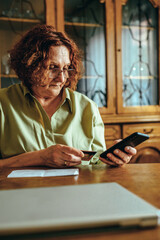 Senior woman using a smartphone and a credit card for online shopping