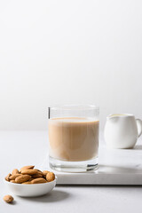 Almond vegan milk and nuts on white background. Lack of cholesterol. Vertical format. Close up. Plant based milk.
