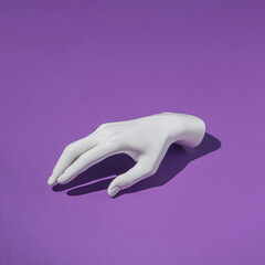 Plastic human hand on purple background. Minimal creative futuristic concept.