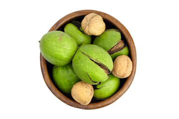 Walnuts with shell in cracked pericarp into wooden bowl isolated on white background, top view