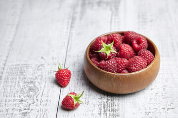 Fresh raspberries in wooden bowl on gray table. Red ripe raspberries, sweet berries
