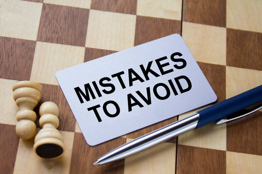 Business card with text Mistakes To Avoid on a chess board with pen and eyeglasses