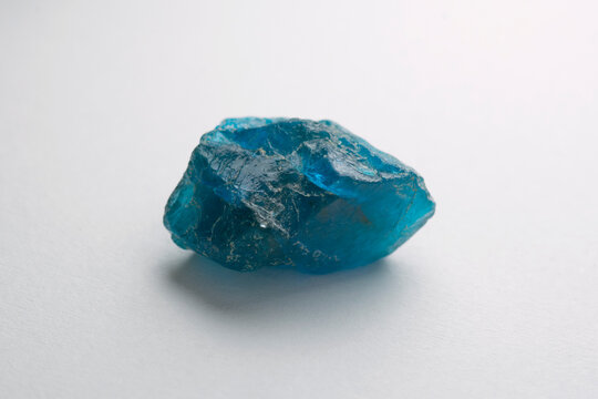 Natural mined raw rough blue color apatite translucent crystal gemstone. Can be polished or faceted. For making jewelry or collection. Light gray gradient background. Gemology theme.