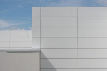 white aluminum panelling on building with blue sky and clouds