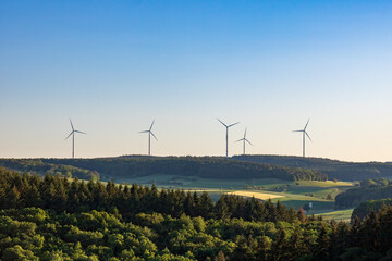 wind turbines in green field against blue sky in summer in Germany. alternative sustainable energy...