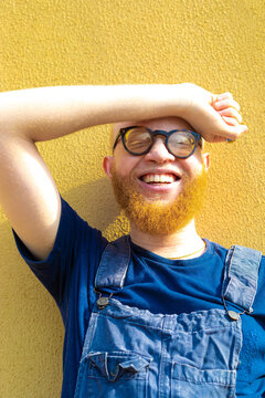 A man laughing on yellow wall. 