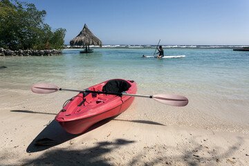 Red kayak on the beach, paddle board on background. Caribbean Authentic Travel in Roatan Honduras