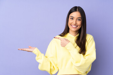 Young caucasian woman over isolated background holding copyspace imaginary on the palm to insert an...