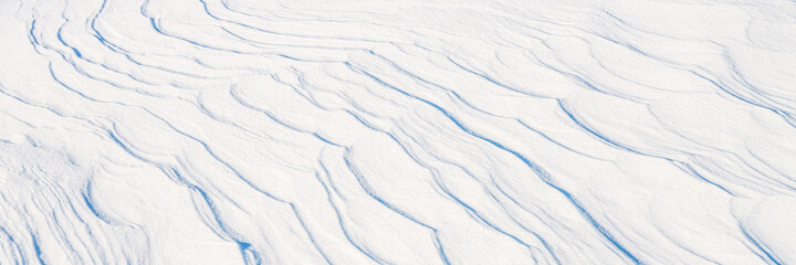 Beautiful winter background with snowy ground. Natural snow texture. Wind sculpted patterns on snow surface. Arctic, Polar region.
