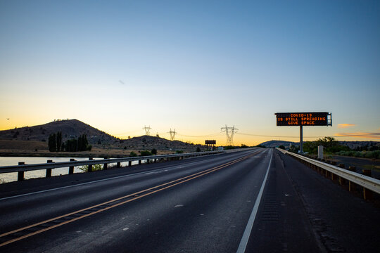 A highway sign warns about covid-19 during the pandemic on a deserted freeway road