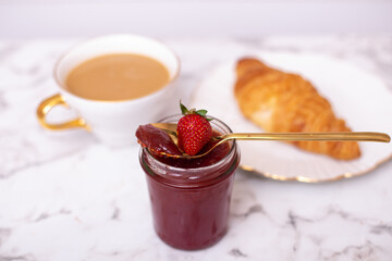 
Coffee cup and sweet croissant with fresh strawberry jam on white table
