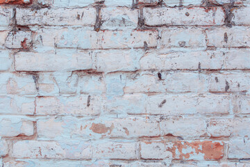 Old ragged wall with peeling blue plaster. Natural damage to dilapidated bricks. Natural environment concept.