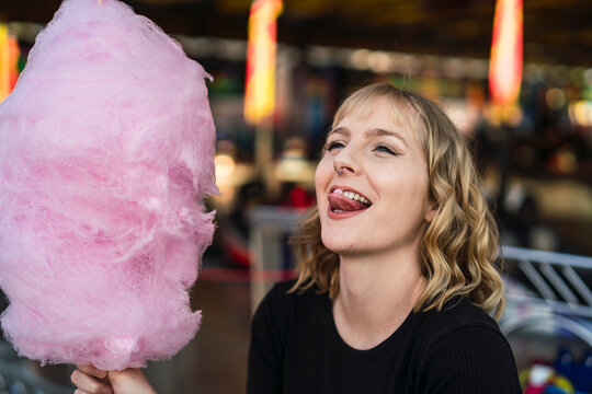 Chica Rubia Guapa Con Algodón De Azucar Rosa Sonriendo En Zona De Atracciones De Una Feria