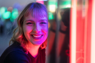 Retrato cercano de chica rubia guapa junto a luces de colores en zona de atracciones de feria