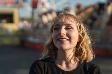 Obraz premium Retrato cercano de chica rubia guapa en zona de atracciones de una feria