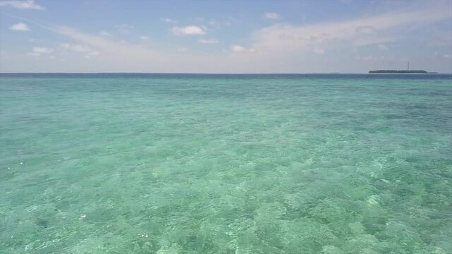 Aerial: Drone Panning Over Turquoise Sea Against Sky On Sunny Day - Vaadhoo, Maldives