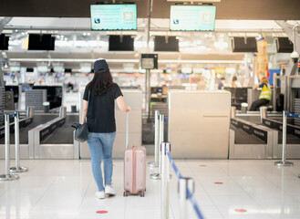 The back view of asian woman traveler carrying luggage prepare to check-in at the counter check in...