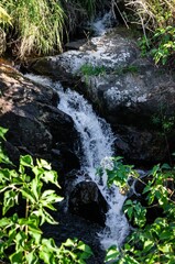 Crystal clear water stream flowing between the rock formations of Mato Limpo waterfall with green vegetation nearby in Cunha, Sao Paulo - Brazil