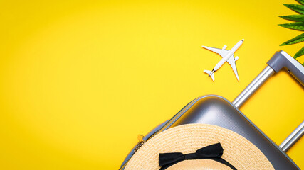 Suitcase, sunglasses with palm leaves and straw hat, white plane in travel composition on yellow...