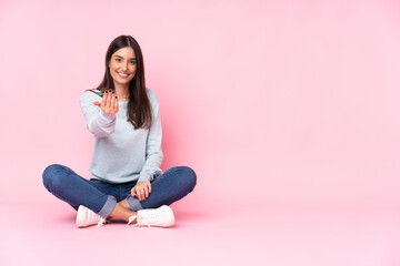 Young caucasian woman isolated on pink background inviting to come with hand. Happy that you came