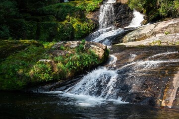 Detail of the water current flowing on rock formations of Ipiranguinha waterfall forming a natural pool right below in the middle of dense Serra do Mar (Sea Ridge) forest. Cunha, Sao Paulo - Brazil.