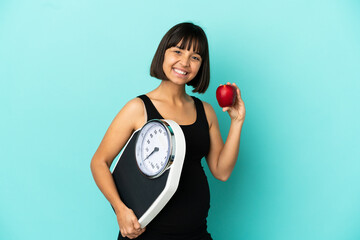 Pregnant woman over isolated background with weighing machine and with an apple