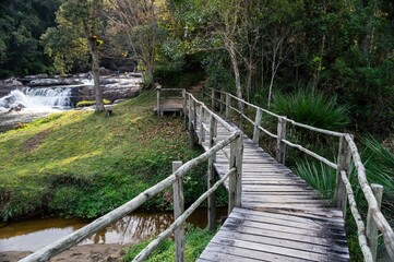 The wood bridge at the beginning of Paraibuna river hiking trail with a waterfall in far back. This is a 1700m self guided trail in Cunha, Sao Paulo - Brazil.