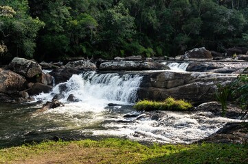 Paraibuna river crystal clear waters flowing around rock formations and creating a waterfall at the beginning of the hiking trail of the river in Cunha, Sao Paulo - Brazil.