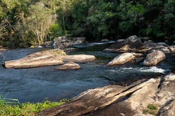 Paraibuna river crystal clear waters flowing around rock formations in the middle of the river and dense Sea Ridge (Serra do Mar) jungle at late afternoon in Cunha, Sao Paulo - Brazil.