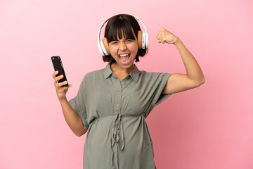 Woman over isolated background pregnant and listening music while celebrating a victory