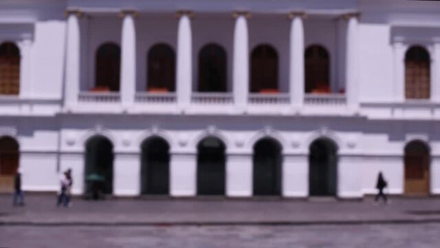 Defocused background of a large square in a city with unrecognizable, blurred people walking over the square