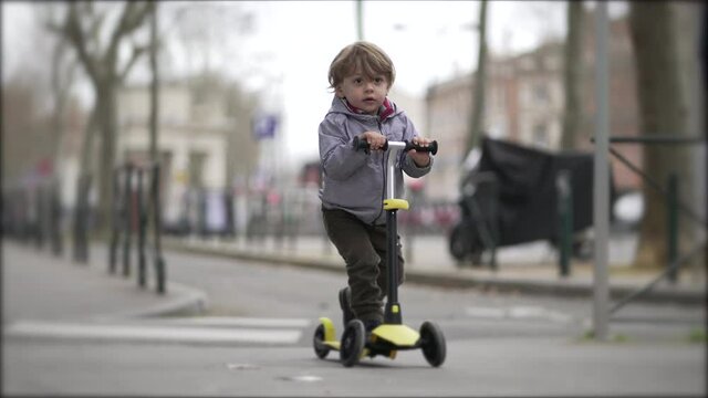 Toddler kid riding scooter in street