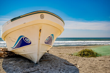 Lancha en la playa de Acapulco, redes y algas en la playa