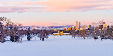 Downtown Denver Skyline from City Park at dawn on a cold January Morning with brightly lit pink and purple clouds over the foothills and the City Park Pavilion in the foreground with a snow covered pa - obrazy, fototapety, plakaty